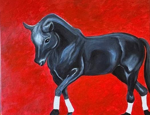 A black bull with a blue sheen standing side on against a flat red ground, head turned toward the viewer, white socks above black hooves.